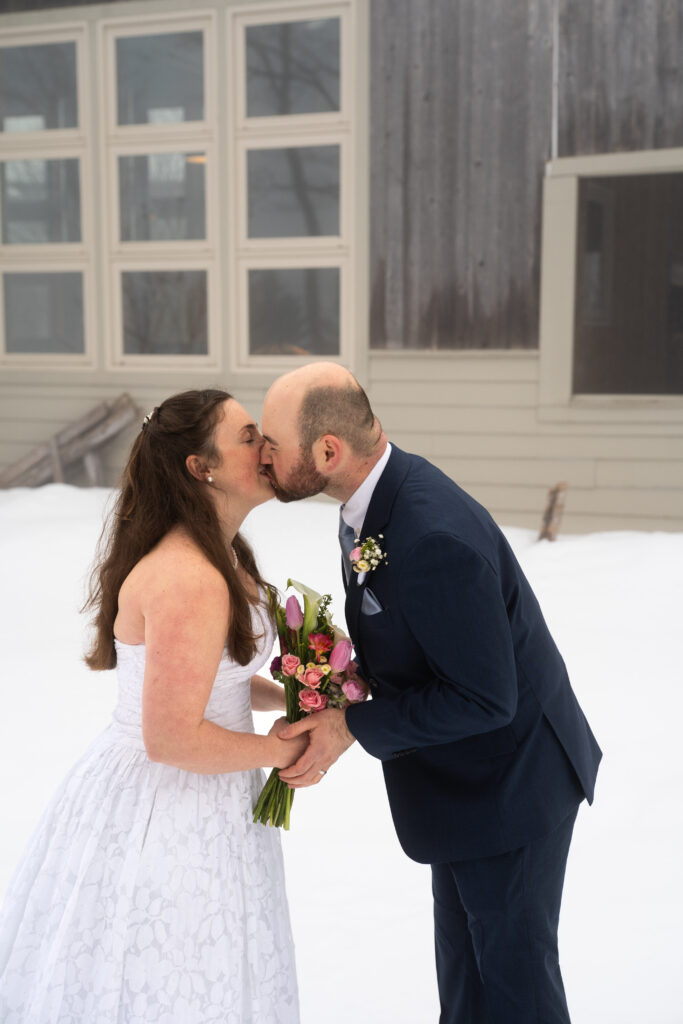 First kiss during winter elopement ceremony with maine Huts and trails 