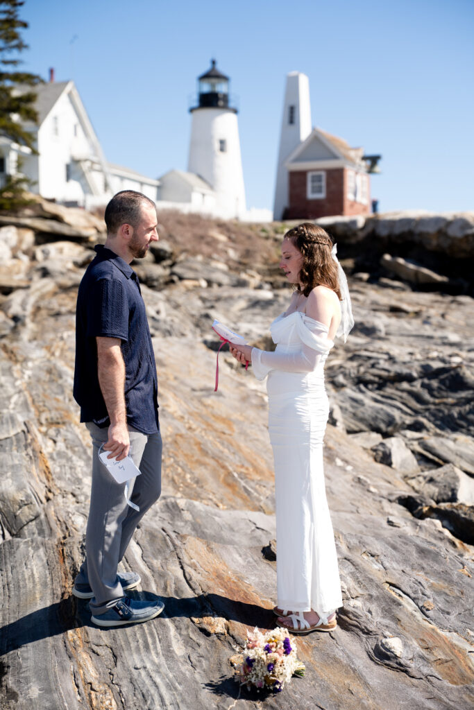  Couple exchanging vows at Pemaquid Point Lighthouse in spring with ocean waves and rocky coastline in Maine