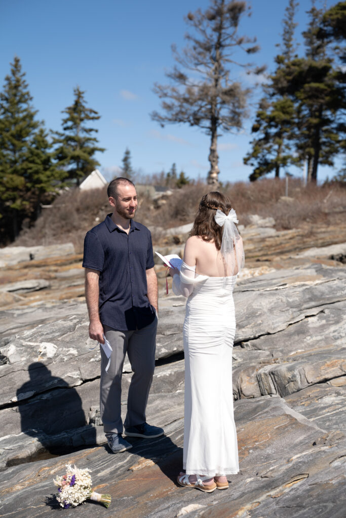 Romantic elopement portraits captured in soft spring light at Pemaquid Point Lighthouse with ocean waves crashing below