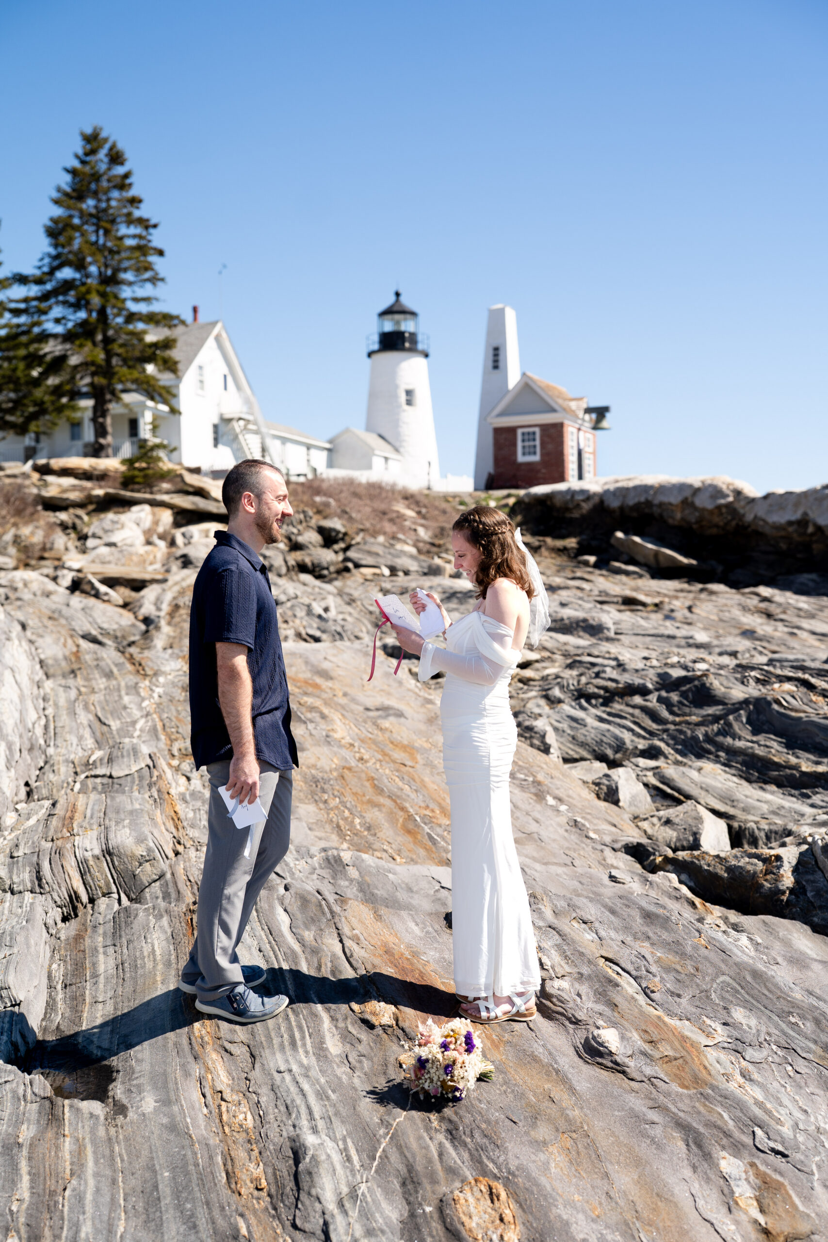 Newlyweds celebrating their elopement at Pemaquid Point Lighthouse near Boothbay Harbor with dramatic Maine coastline views