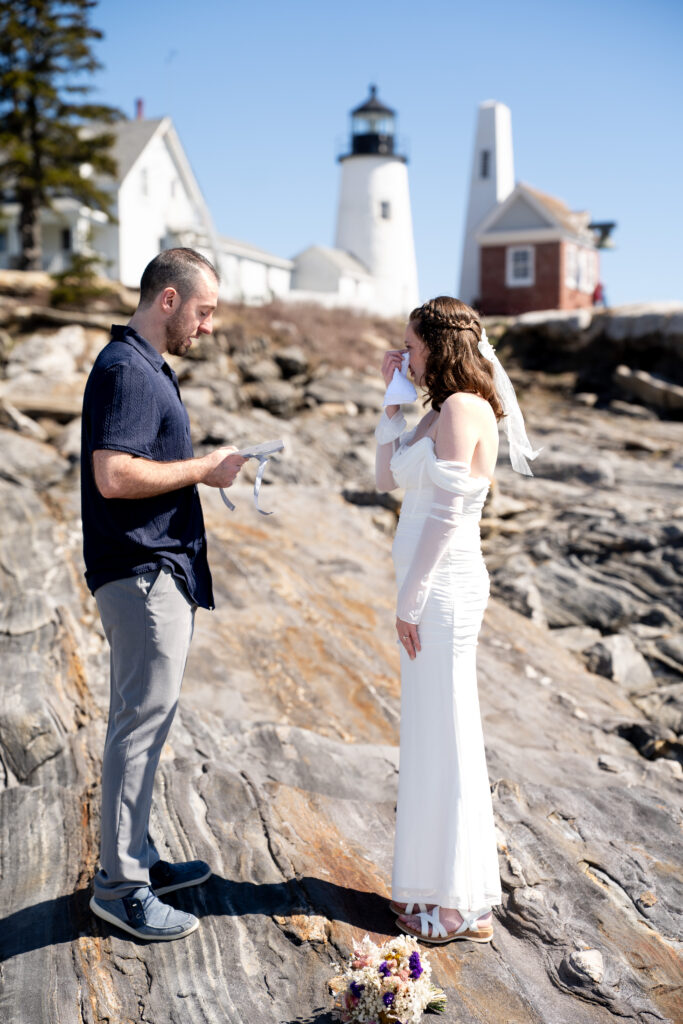 Bride and groom posing for portraits at Pemaquid Point Lighthouse in spring with rugged Maine coastline scenery