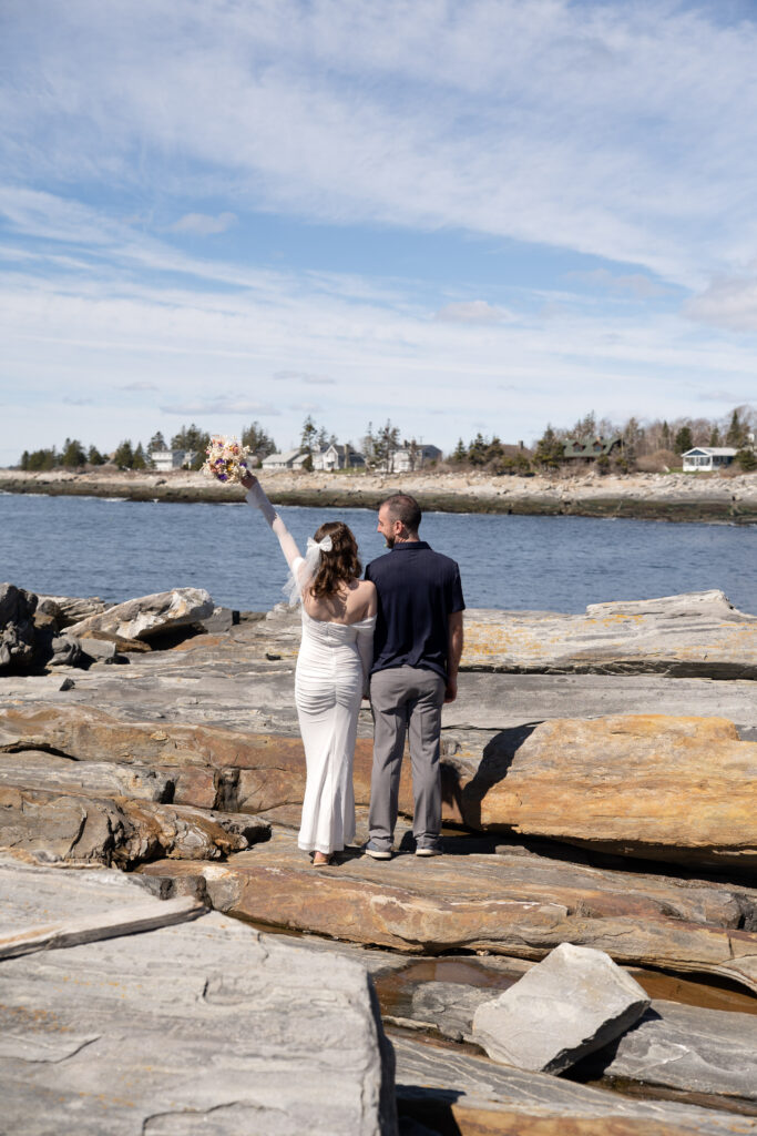  Intimate wedding moment captured at Pemaquid Point Lighthouse during spring with wild coastal winds and ocean backdrop

