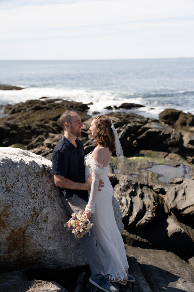 Couple exchanging rings during elopement ceremony at Pemaquid Point Lighthouse overlooking Boothbay Harbor area