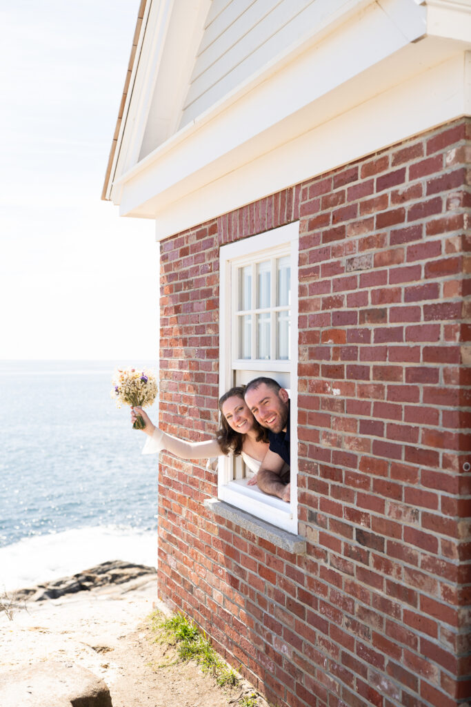 Bride and groom standing at Pemaquid Point Lighthouse during golden spring light over the Atlantic Ocean